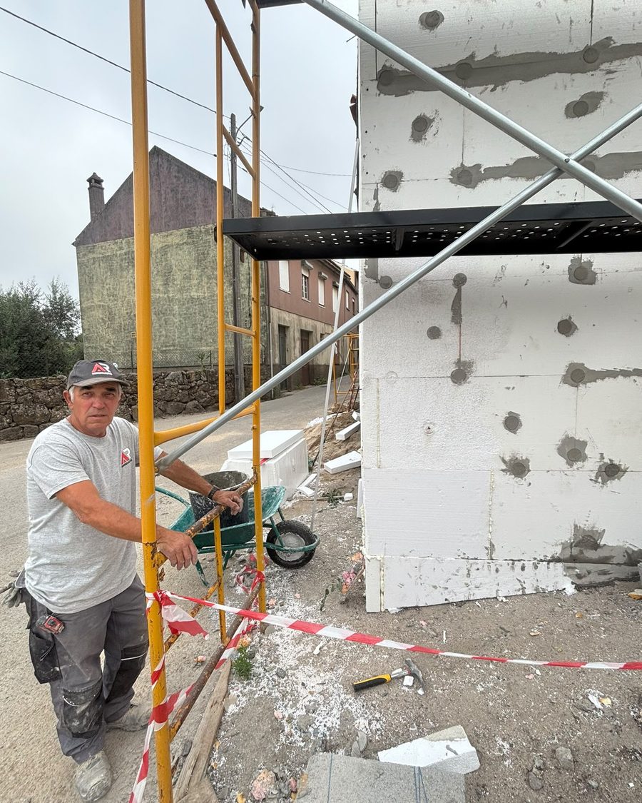 Elemento da equipa junto à fachada com as placas de isolamento colocadas e os andaimes montados
