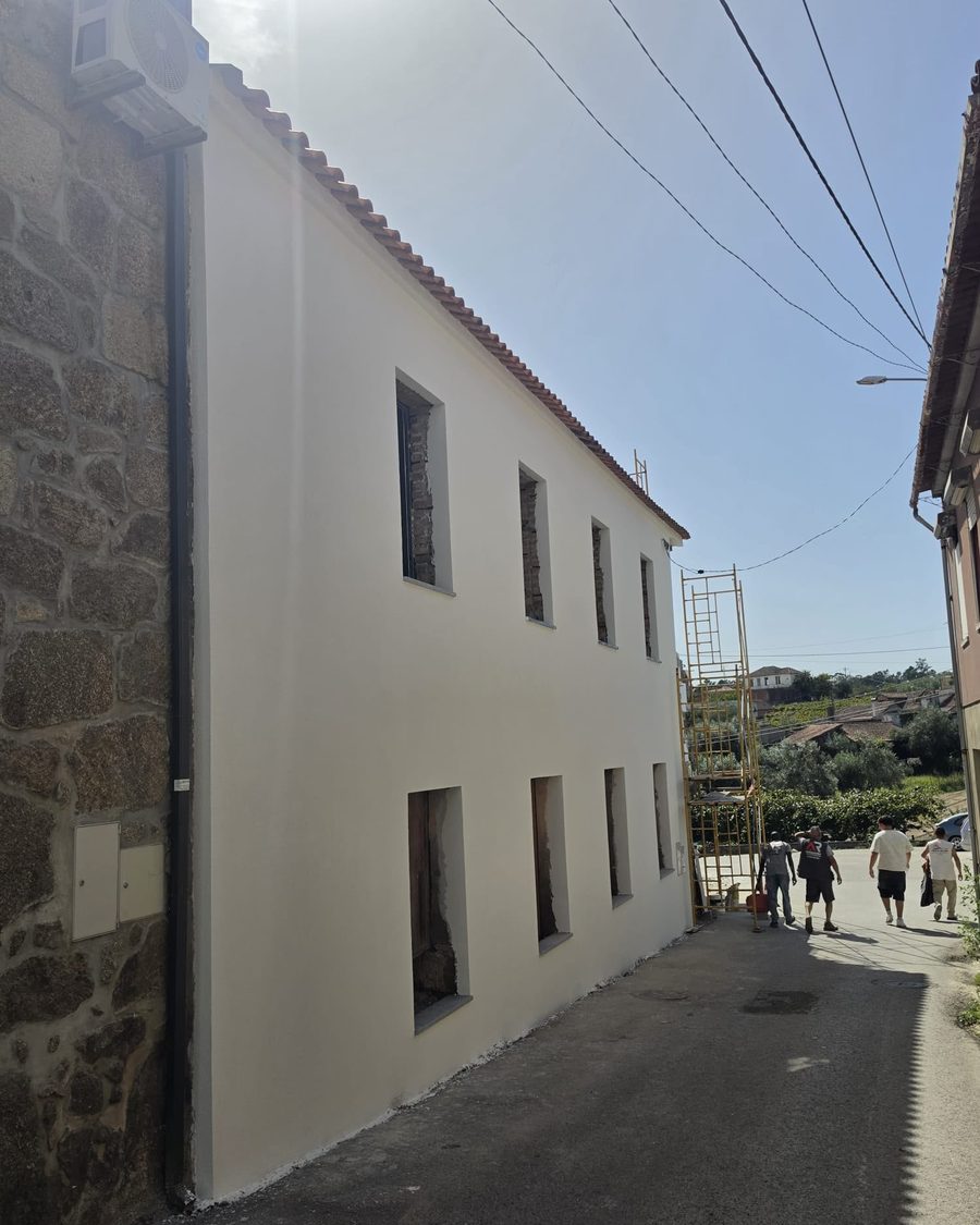 Casa de dois pisos com a fachada isolada e pintada de branco