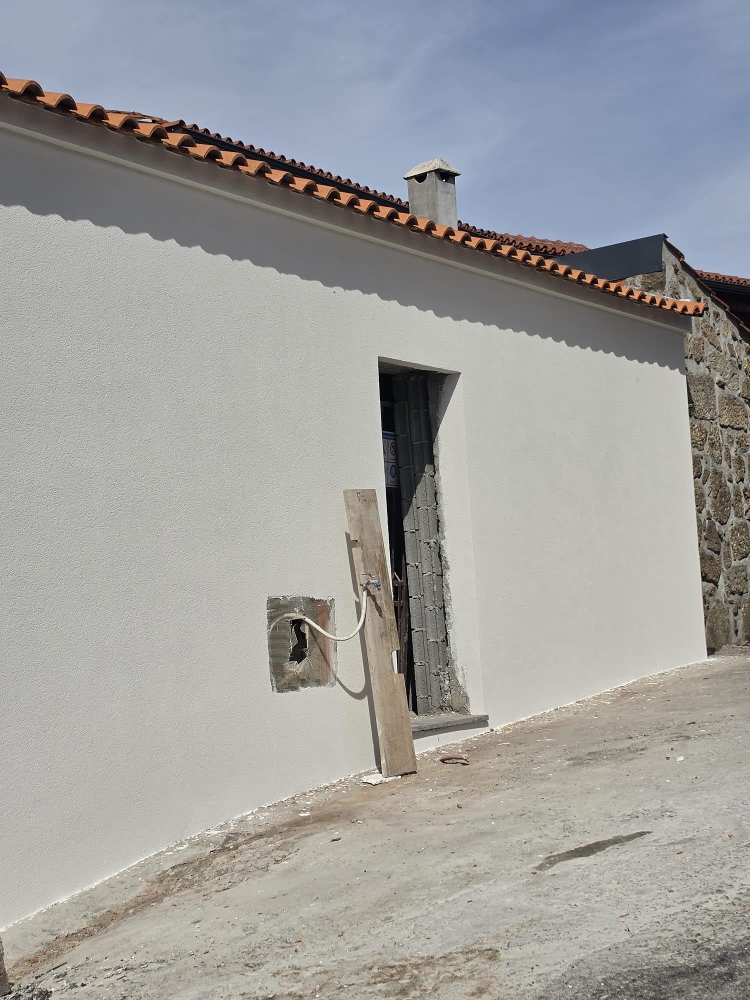 Moradia térrea com a fachada rebocada e pintada de branco e o telhado de telha