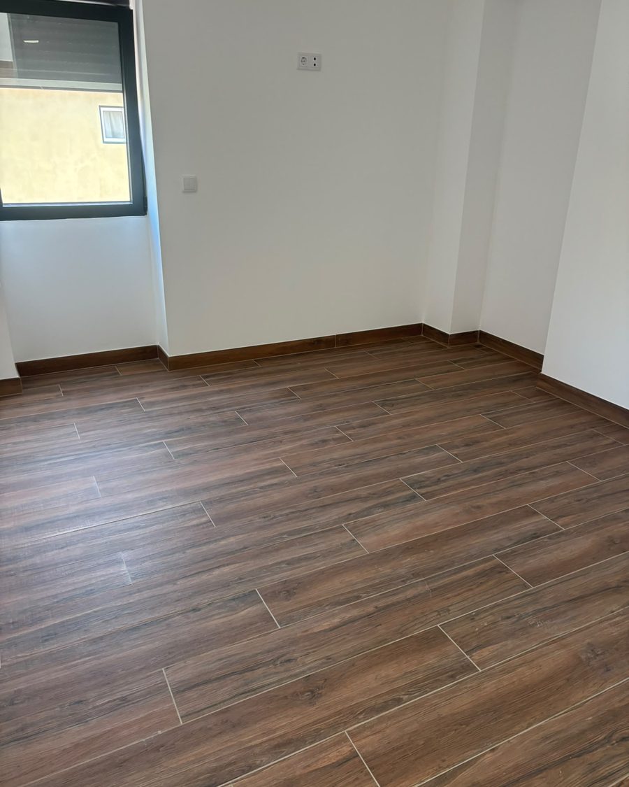 Quarto vazio com pavimento cerâmico efeito madeira e rodapé a condizer
