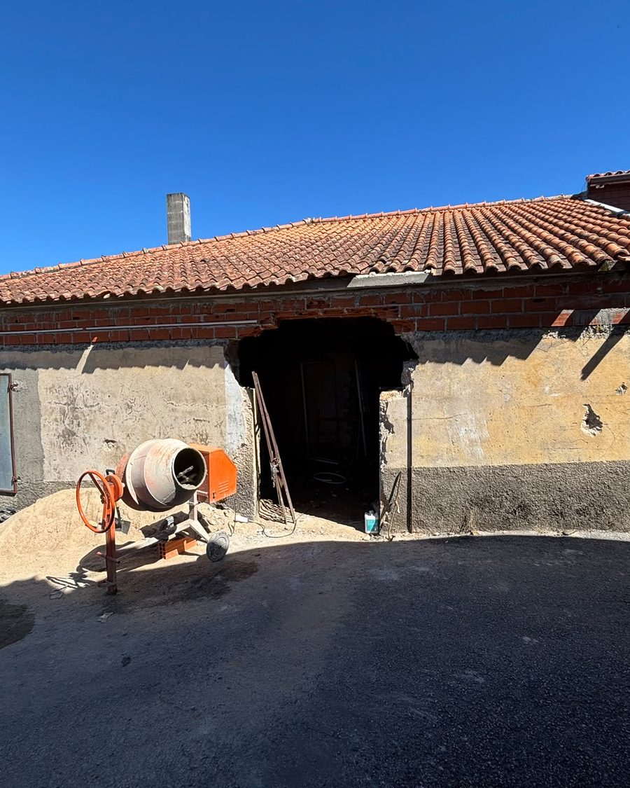 Moradia em obra, com betoneira e areia à porta