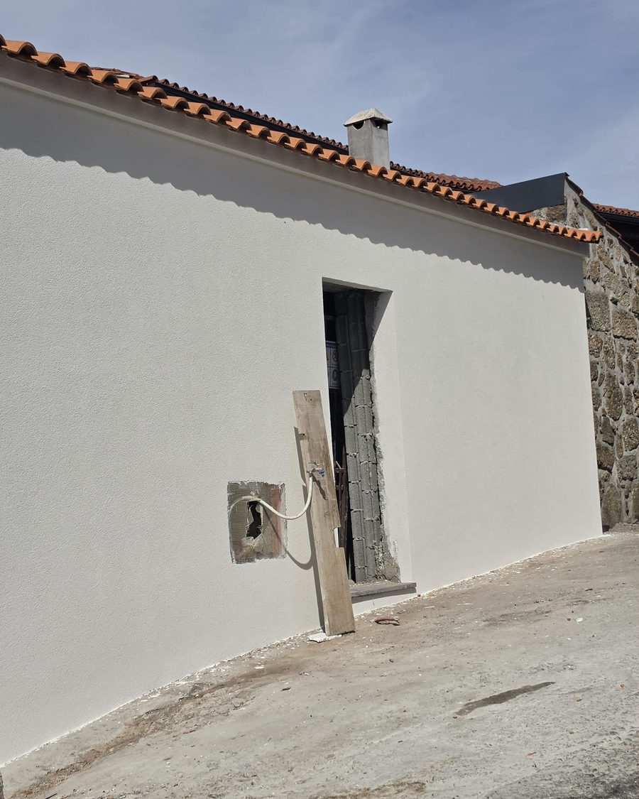 Moradia térrea acabada, pintada de branco, com o telhado de telha