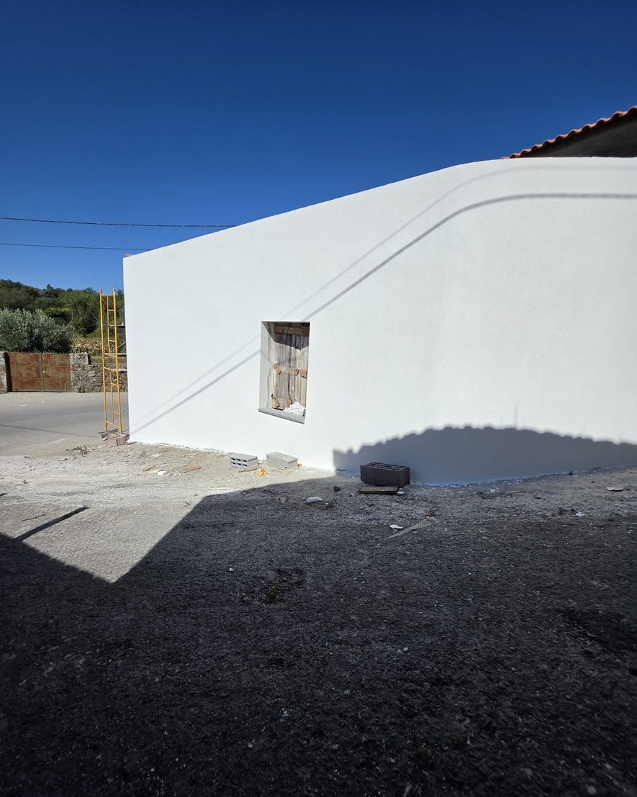 Muro curvo rebocado e pintado de branco junto à moradia